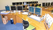 A large desk curved round in a semicircle housing five computer monitors and audio equipment.