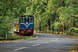 Un train tiré par une locomotive diesel sur les bords d'une route.