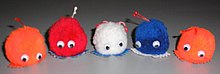 Five fluffy Weepul toys with a pair of googly eyes each; orange, red, white, blue, and orange in order, all with white and black googly eyes