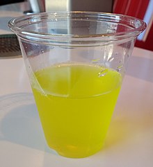 A clear plastic cup, filled roughly halfway with a slightly opaque yellow/green liquid