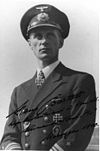 A man wearing a military uniform, peaked cap, and an Iron Cross displayed at the front of his uniform collar.