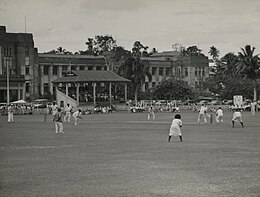 photo en noir et blanc représentant des gens habillés de blanc attendant le lancer d'une balla de cricket