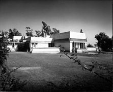 Hollyhock House desde cuesta abajo con niños jugando en la piscina, 1921