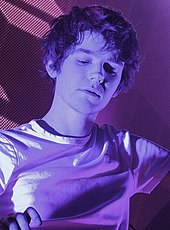 Madeon playing at a DJ booth.