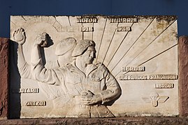 Photographie d’une plaque funéraire représentant un joueur de pelote lançant une grenade offensive.