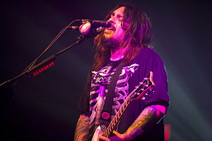 Shaun Morgan wearing a black print t-shirt, playing electric guitar and singing into a microphone onstage