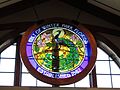 Stained glass depicting the Winter Park city seal, consisting of a peacock standing on a branch under the sun