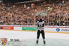 Joueur du HC Ajoie soulevant une Coupe devant des supporters