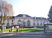 Façade d'un bâtiment avec corps central et deux ailes.