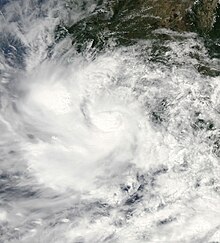 A satellite image of a tropical storm very near the Pacific coast of Mexico; much of the associated cloud cover is already over land