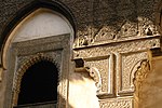 Carved wood and stucco around one of the windows along the upper level of the courtyard