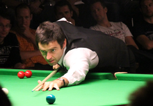 Ronnie Sullivan leaning across a table lining up a shot