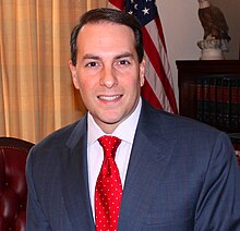 Tom Basile smiling for a photo, wearing a business suit