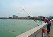 Hand lift net operated by a man on a bridge over Nandu River, Hainan, China