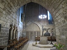 Photo : baptistère au centre d'une salle voûtée.