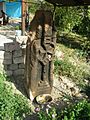 Khachkar a pilastro con una croce di Malta dietro ad una casa nel paese.