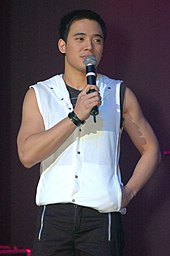A photo of Santos in a white sleeveless shirt with a hand-held microphone
