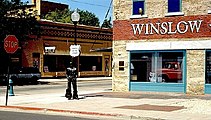 The "standin' on the corner" statue and mural in downtown Winslow commemorates the Eagles' song "Take It Easy". The southbound corridor of State Route 99 (West 2nd Street) is visible in the background.