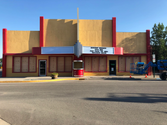 A deserted yellow and red theater with boarded windows, and a blue crane to the right of the image.