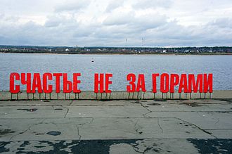 "Happiness is coming soon" in red letters on a riverbank