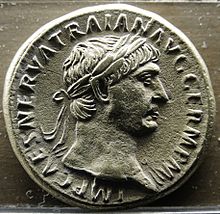 pièce de monnaie en métal gris, présentant un jeune homme de profil aux cheveux ceints d'une couronne de laurier, entouré d'inscriptions.