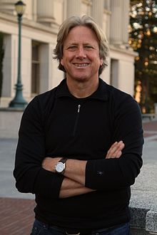 Dacher Keltner wearing a dark sweater, squinting and grinning at camera