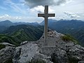 Monte Tombea, ai piedi della croce, posta a ricordo di tutti i malgari di Magasa che nei secoli monticarono la malga Tombea, reca la scritta 29 settembre 2013. Sullo sfondo Cima Rest, Monte Camiolo, Moerna, la Val Vestino, il sud del lago di Garda con la penisola di Sirmione e da destra il monte Denervo, monte Castello, monte Pizzocolo e il monte Spino