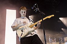 Sam Fender playing guitar with a white T-shirt