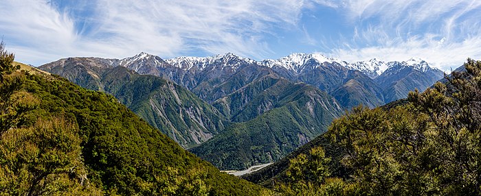 Derrière des pentes déjà raides, de hautes montagnes, neigeuses dans les sommets, boisées dans les vallées, abruptes partout, se dressent sous un ciel échevelé.