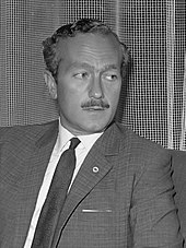 Black and white photograph of Colin Chapman in formal uniform and speaking to a man on his left