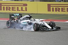 A Formula One car with smoke coming from the front right tire after a brake lockup