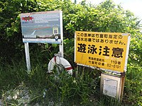 海岸入口の看板とAED。右側の看板は、赤色の「遊泳禁止」と黄色の「遊泳注意」（遊泳可能時）に差し替えられる。