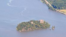 Pollepel Island seen at a distance from above, eastern shoreline of Hudson River with train tracks are on the right half of image