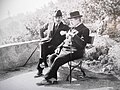 Deux hommes assis sur un banc avec chapeaux et cannes en train de discuter.