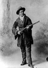 Woman in western style clothes holding a rifle