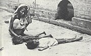 A girl sits on a street next to the bodies of two other malnourished children