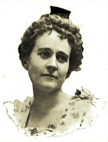 B&W portrait photograph of a woman with her hair in an up-do, wearing a white blouse