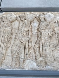 Three young men holding "hydriai" (water jugs), part of the Panathenaic procession depicted in the Parthenon frieze.