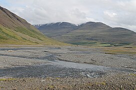 a shallow river following through a rocky valley floor