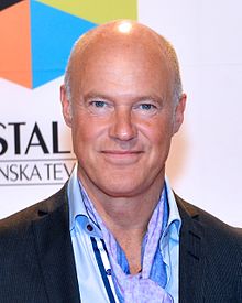 Stefan Wernström wearing a light-coloured shirt, dark suit jacket, and a neckerchief, looking directly at camera