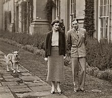 Photographie en noir et blanc montrant une femme et un homme se promenant dans un parc.