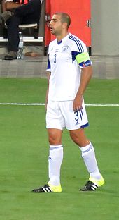 A photograph of a white man wearing association football attire while clapping his hands.