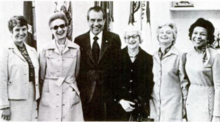 Richard Nixon posed standing and smiling in the Oval Office with five recipients of the 1974 Federal Woman's Award; from left, Brigid Leventhal, Madge Skelly, Nixon, Henriette Avram, Gladys Rogers, and Roselyn P. Epps