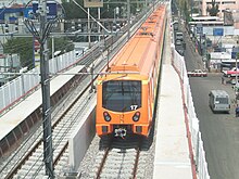 A steel-wheeled train leaves a station.