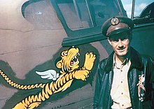 Photographie couleur de Robert Smith devant son P40. L'emblème de l'escadrille, un tigre avec des ailes et les griffes sorties, est visible.