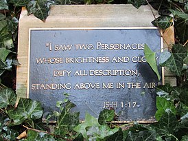 a black plaque surrounded by leaves with gold letters reading: "I saw two personages whose brightness and glory defy all description, standing above me in the air."