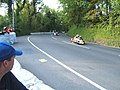 View from Sarah's Cottage uphill towards the Creg Willey's area, with sidecars returning to Paddock in wrong direction after a Red Flag race stoppage caused by a competitor crash during 2009[original research?]