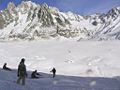 Skieurs de la Vallée Blanche dominant la jonction entre les glaciers du Tacul (en bas à droite) et de Leschaux (en haut à droite) donnant naissance à la Mer de Glace (à gauche) ; au fond, de gauche à droite, les Drus, l'aiguille Verte et le glacier de Talèfre.