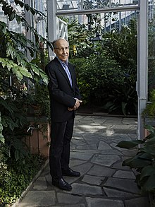 Photo of Kari K. Alitalo standing among greenhouse plants.