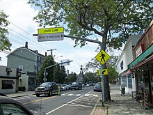Pedestrian crossing on two lane highway going through Sayville. "State Law - Yield to Pedestrians" sign over the roadway and crosswalk.